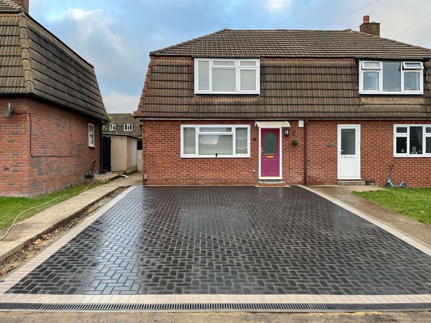 Charcoal herringbone block paving driveway in front of a brick house
